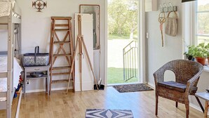 A room with a wooden floor, a wicker chair, a ladder, a tripod, and a door leading outside. - 6 Person Holiday Home in Ullared (Ullared)