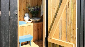 A rustic wooden cabin interior with a wooden bench, a large bowl, and a vase on a counter. - 6 Person Holiday Home in Ullared (Ullared)