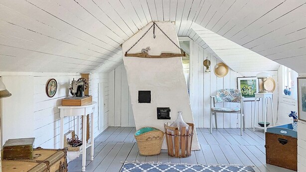 A cozy attic room with wooden beams, a patterned rug, and rustic decor including a vintage sewing machine and a wooden chest. - 6 Person Holiday Home in Ullared (Ullared)