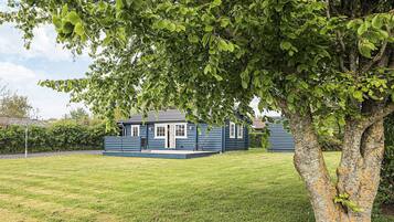 A blue wooden house with a lawn in front.