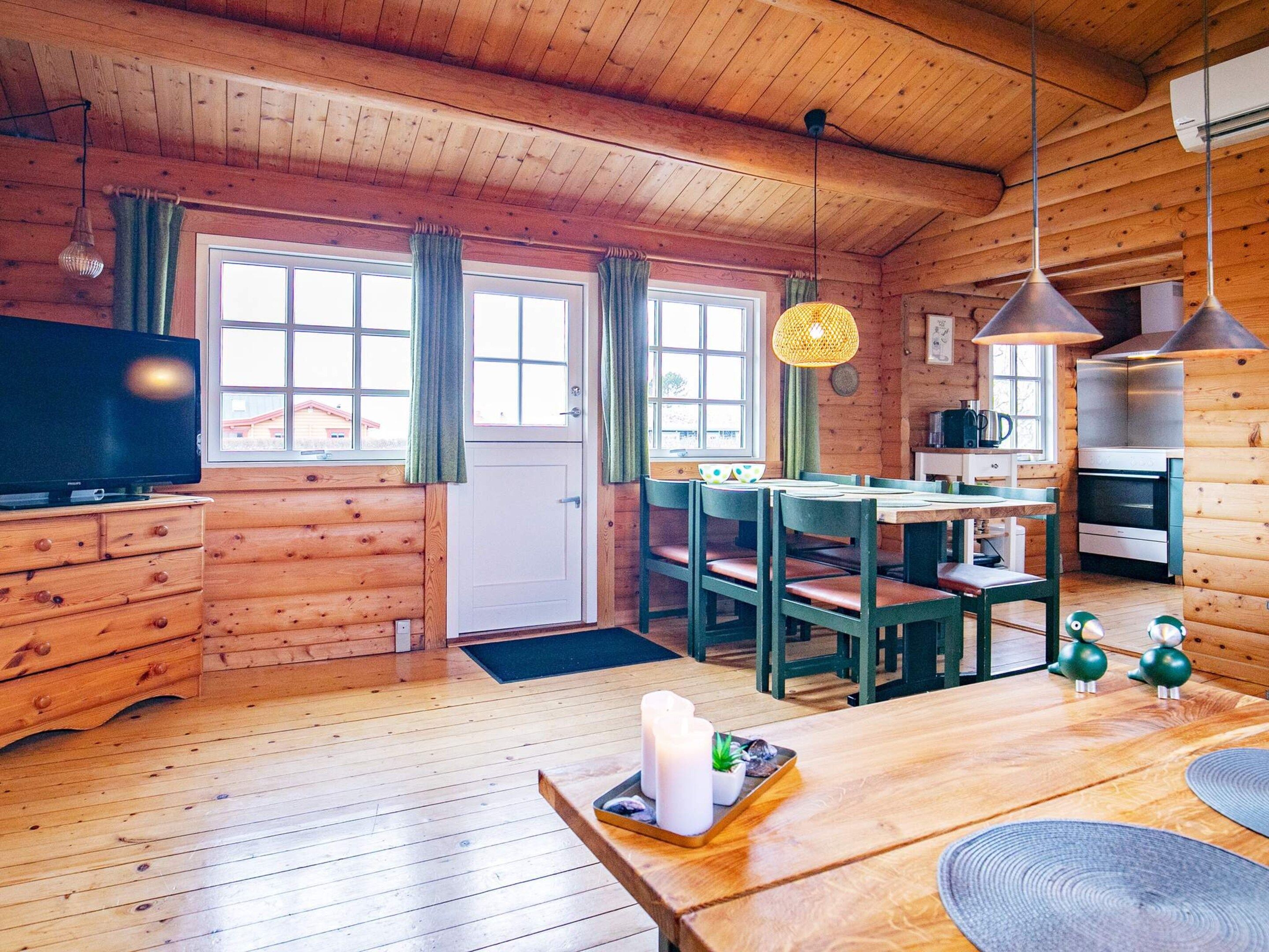 Ein Interieur einer Holzhütte mit Essbereich, Küche und Fernseher.