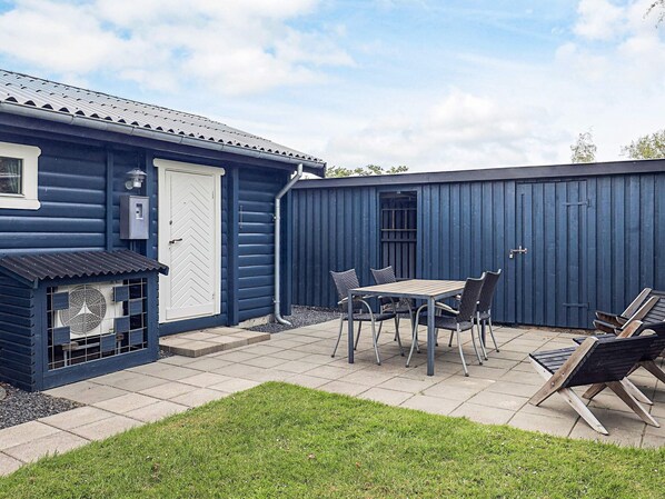 Ein blaues Gebäude mit einer Terrasse, einem Tisch mit Stühlen und einem Grill.