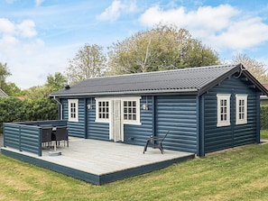 A small, single-story house with a dark blue exterior, white trim, and a wooden deck.