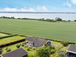 A residential area with a house featuring a large deck and a view of a lake. - 4 Star Holiday Home in Svendborg (Svendborg)