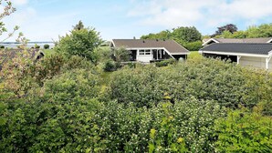 Een woonwijk met huizen, een tuin en een waterpartij op de achtergrond.