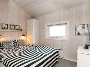 A bedroom with a bed, a window, a wardrobe, and wall-mounted artwork. - 4 Star Holiday Home in Svendborg (Svendborg)