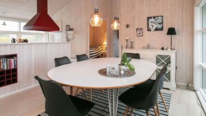 Een moderne eetruimte met een ronde tafel, zwarte stoelen en hanglampen.