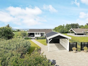 Uma casa moderna com garagem, área externa coberta e vista para o mar.