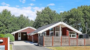 A two-story building with a red exterior, a gravel driveway, and a wooden fence.