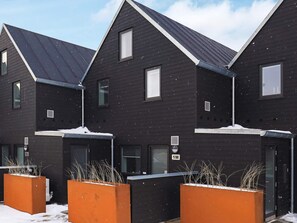 Un immeuble résidentiel moderne, doté d’un revêtement en bois foncé, de nombreuses fenêtres et d’un toit en pente.