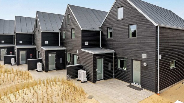 Un bâtiment moderne comprenant plusieurs logements, chacun se caractérisant par une façade sombre, de grandes fenêtres et un toit plat.
