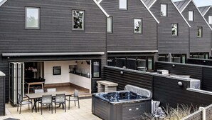 Un immeuble résidentiel moderne doté d’un patio comprenant un jacuzzi, un espace salon extérieur et une cuisine.