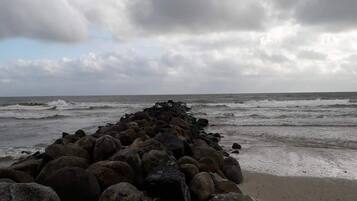 A rocky breakwater extending into the sea with waves crashing against it.