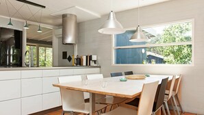 Una cucina moderna con una grande isola, mobili bianchi e vista sull'esterno attraverso una finestra.