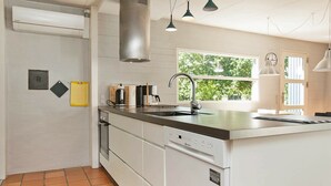 Una cucina moderna con un'isola grande, mobili bianchi e vista sul verde.