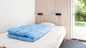 Una camera da letto con un letto, una parete in legno e una finestra vista verde.
