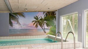 Piscina con vista su una spiaggia e palme, una finestra e una scala in metallo.