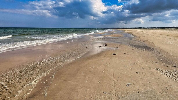 A beach with a wide sandy shore, waves, and a partly cloudy sky. - Holiday Home in Jerup (Jerup)