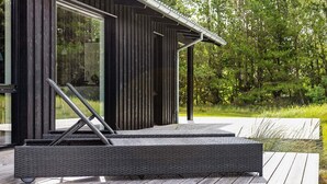 A modern wooden cabin with a large glass door, a covered outdoor seating area, and a deck. - Holiday Home in Jerup (Jerup)