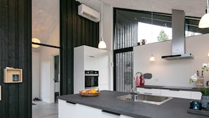 A modern kitchen with a central island, built-in ovens, and pendant lighting. - Holiday Home in Jerup (Jerup)