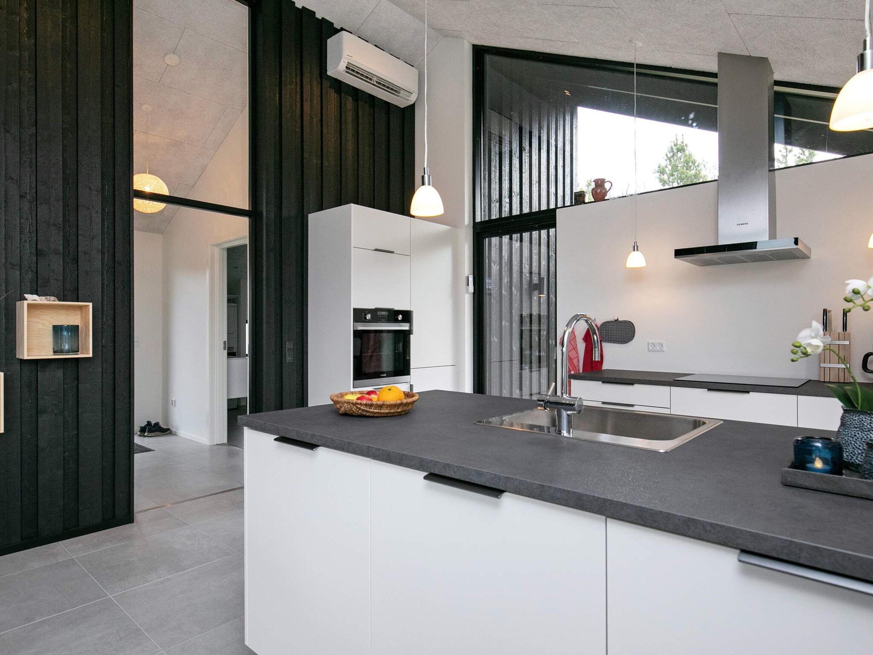 A modern kitchen with a central island, built-in appliances, and pendant lighting.