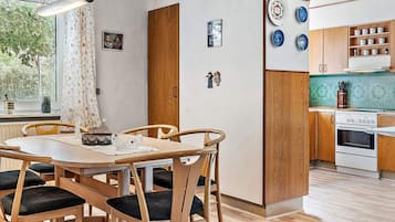 Una cocina moderna con armarios de madera, horno integrado y comedor con mesa y sillas de madera.