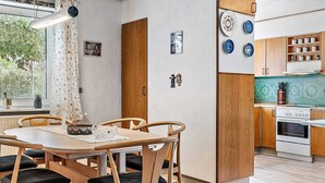 Una cocina moderna con armarios de madera, horno integrado y comedor con mesa y sillas de madera.