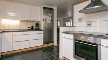 A modern kitchen with white cabinetry, a stainless steel refrigerator, a built-in oven, and a coffee maker on the countertop.