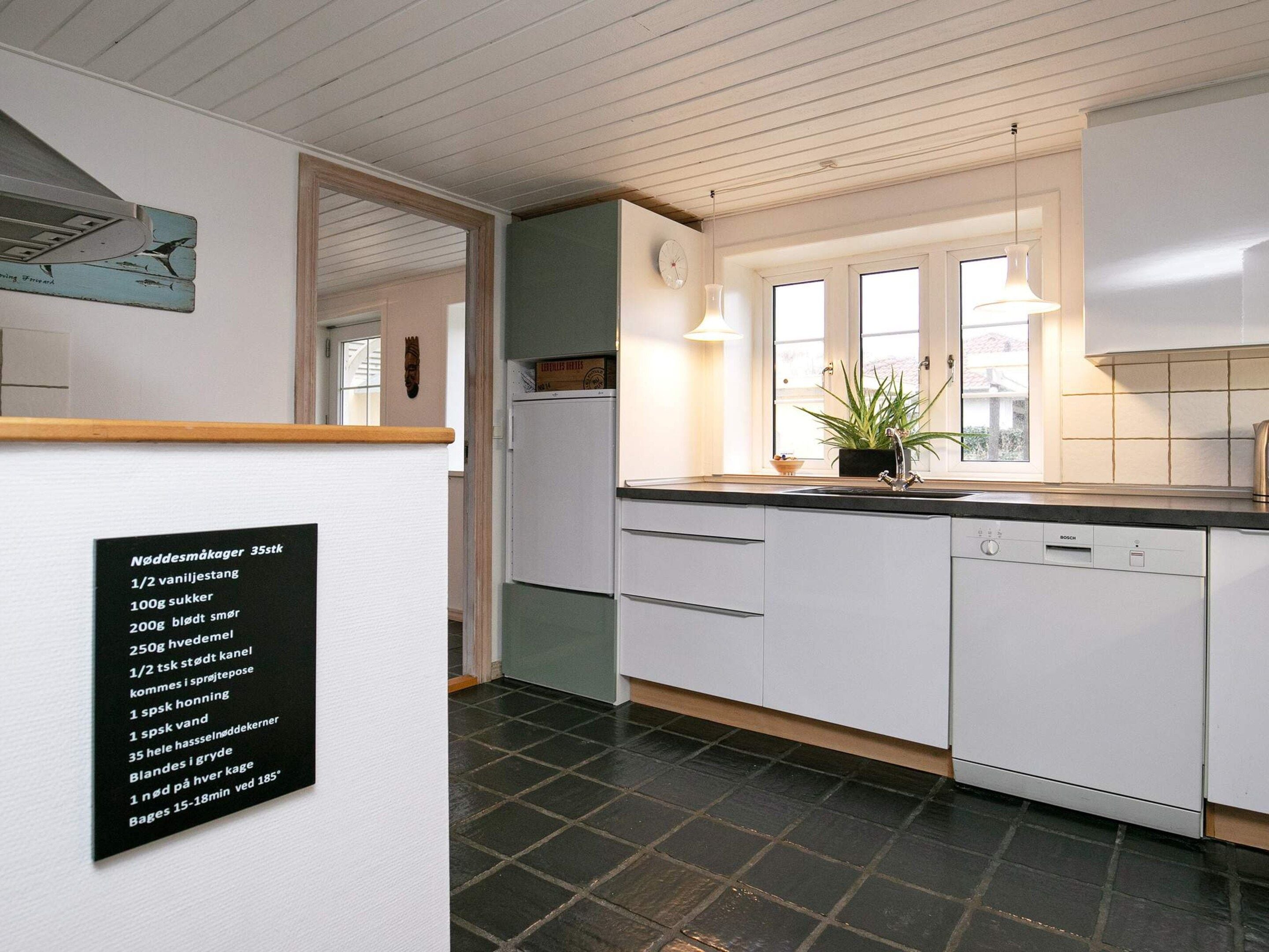Eine moderne Küche mit weißen Schränken, einem Geschirrspüler von Bosch und einem Fenster für natürliches Licht.