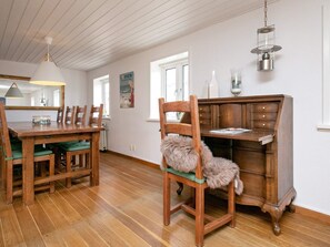 A dining area with a wooden table and chairs, a wooden cabinet, and a hanging light fixture. - Holiday Home in LÃ¸kken (Lokken)