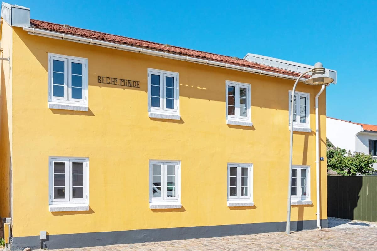 A yellow building with multiple windows and a sign reading 'BECH & MINDE'.