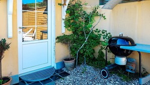 A patio with a grill, a door, and a small tree. - Holiday Home in LÃ¸kken (Lokken)