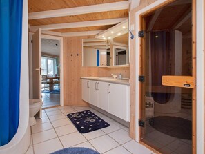 A bathroom with a toilet, sink, mirror, and wooden ceiling.