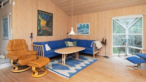 A cozy room with a wooden interior, a blue sofa, a wooden chair, a small table, and a large window. - Holiday Home in NykÃ¸bing Sj (Nykobing Sjaelland)