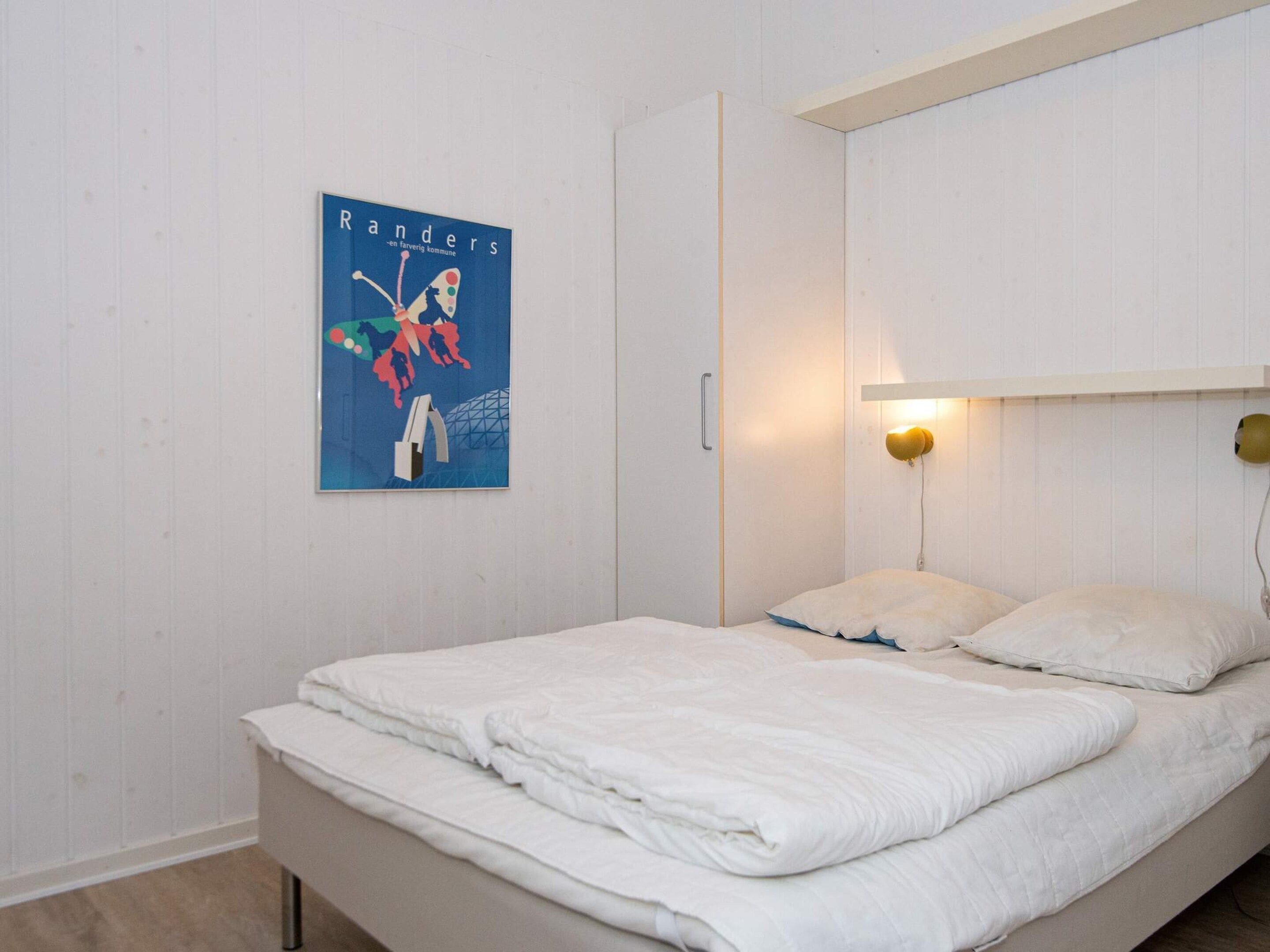 A bedroom with a bed, a wall-mounted light, and a poster.