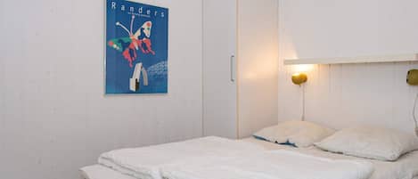 Ett sovrum med en säng, en vägglampa och en affisch.