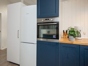 A kitchen with a white Bosch refrigerator, a built-in oven, and a coffee maker on the counter. - 4 Star Holiday Home in Glesborg (Glesborg)