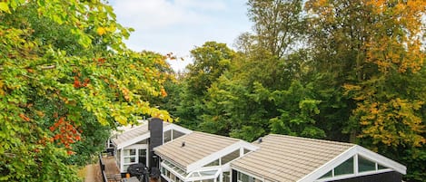 A modern house with a glass conservatory, a wooden deck, and a black exterior.