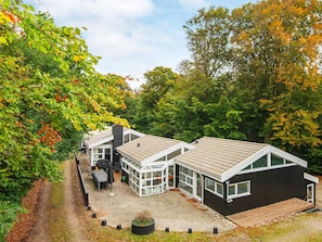 A modern house with a glass conservatory, a wooden deck, and a black exterior.