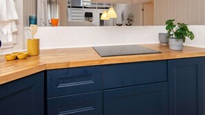 Une cuisine moderne avec un plan de travail en bois, des meubles de couleur bleu foncé et une grande fenêtre.
