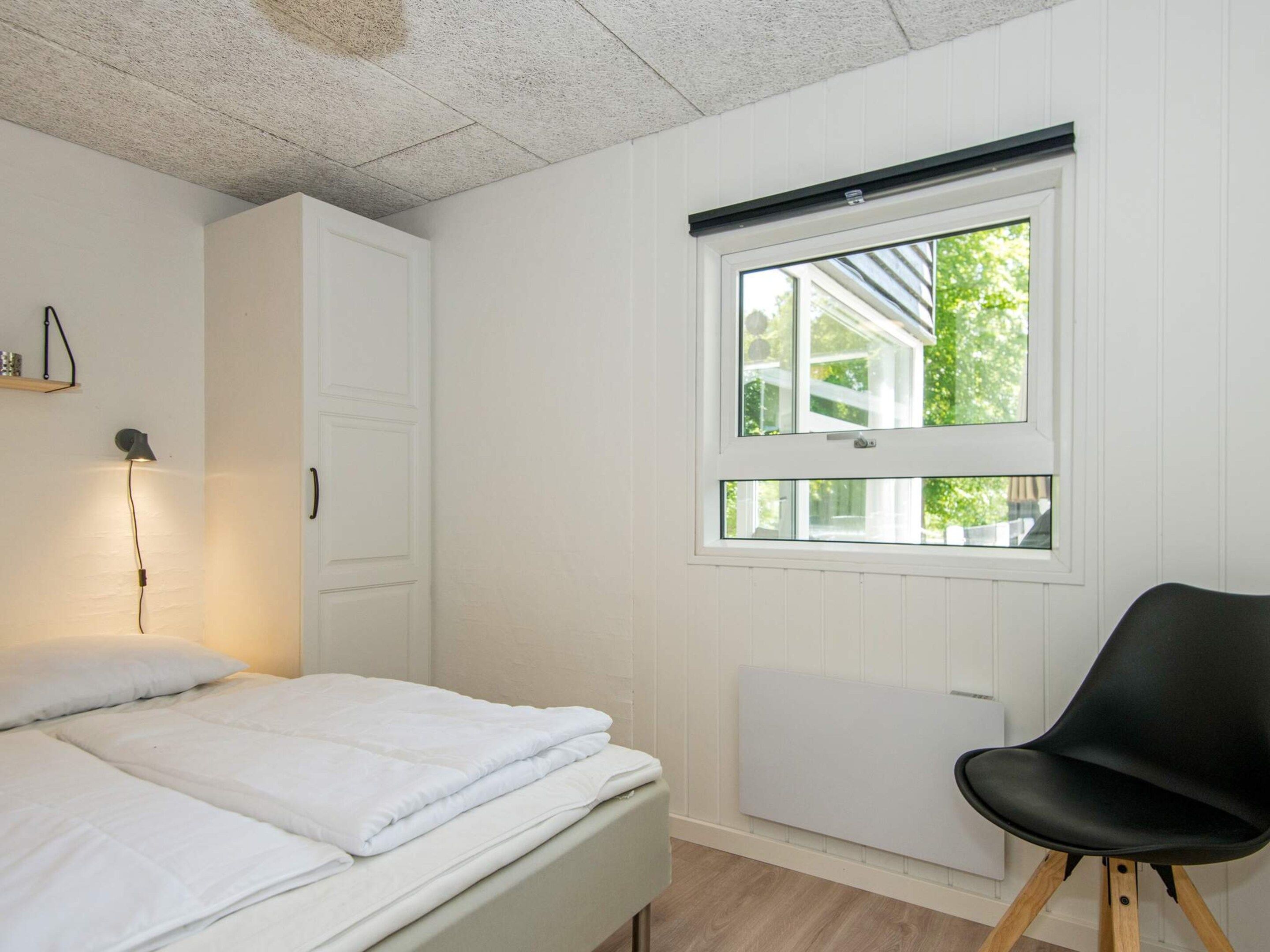 Ein Schlafzimmer mit einem Bett, einem Sessel, einem Fenster und einer Heizung.