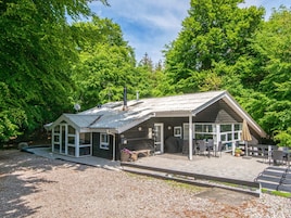 A rustic cabin with a covered porch, a chimney, and a number '23' sign.