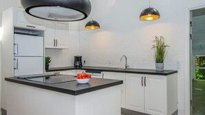 A modern kitchen with white cabinetry, a central island, black countertops, and pendant lighting. - 4 Star Holiday Home in Glesborg (Glesborg)