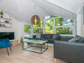 A modern living room with a flat-screen TV, a sofa, a coffee table, and a hanging light fixture.