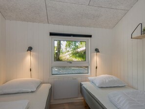 A bedroom with two beds, a window with a view of trees, and wall-mounted lamps. - 4 Star Holiday Home in Glesborg (Glesborg)