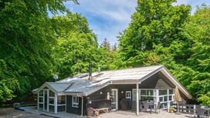A lodge with a covered patio, a chimney, and a number 23 sign. - 4 Star Holiday Home in Glesborg (Glesborg)