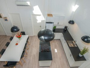 A modern kitchen with a central island, white cabinetry, and black pendant lighting. - 4 Star Holiday Home in Glesborg (Glesborg)