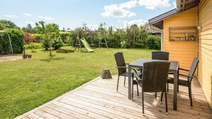 A wooden deck with outdoor furniture, a slide, and a garden with various plants. - 6 Person Holiday Home in Hadsund (Hadsund)