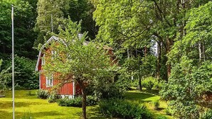 A red barn surrounded by lush greenery and trees. - 4 Person Holiday Home in Karlsborg (Karlsborg)