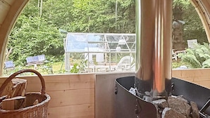 A cozy room with a large window, a Harvia wood stove, a wicker basket, and a wooden chair. - 4 Person Holiday Home in Karlsborg (Karlsborg)